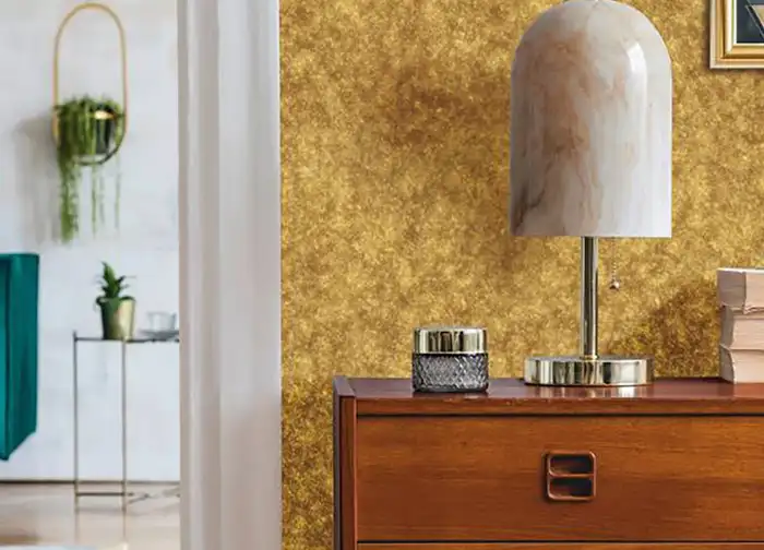 Wohnraum mit goldener Glitter-Wandverkleidung, Holzkommode und Designerlampe – edles Interior Design mit Cover Styl Möbel- & Dekorfolie im Metallic-Glitter-Look.