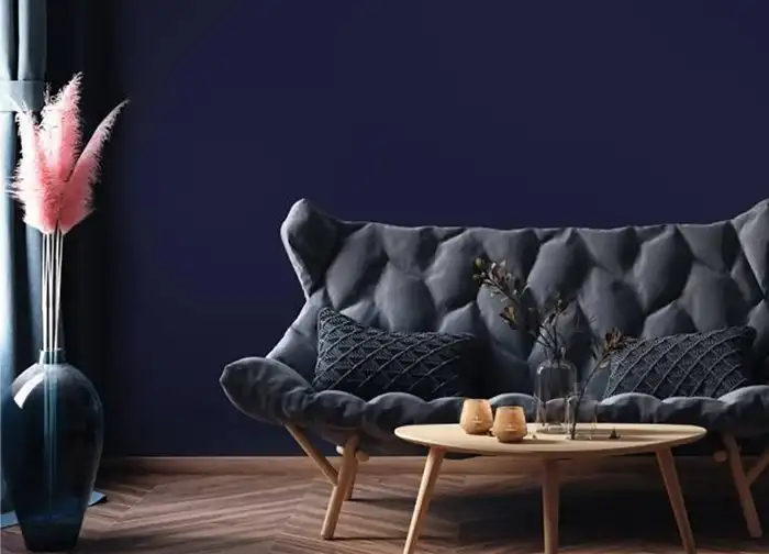 Modernes Wohnzimmer mit dunkelblauer Wand in Uni-Farbe, grauem Sofa, Holztisch und dekorativen Elementen – stilvolles Interior Design mit Cover Styl Möbelfolie in einfarbiger Optik.