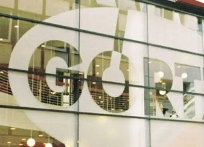 Schaufensterbeschriftung mit weißer Plotterfolie auf Glasfassade, großflächiges Logo aus selbstklebender Farbfolie auf moderner Gebäudefront