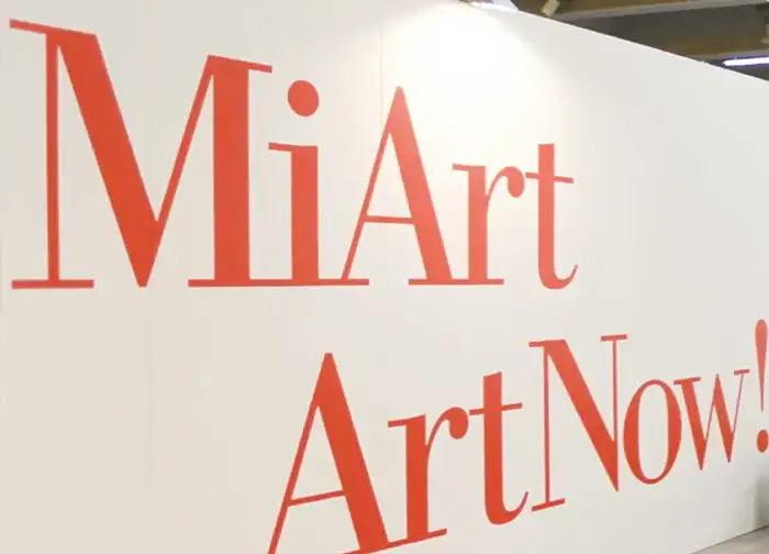 Schilderbeschriftung mit roter Plotterfolie auf weißer Wand, präzise geschnittene Schriftzüge für Messe- oder Werbedisplay