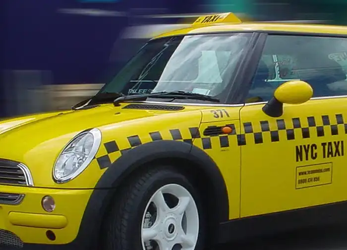 Fahrzeugbeschriftung mit schwarzer Plotterfolie auf gelbem Taxi, präzise Foliengrafik für Werbung und Car Wrapping im Straßenverkehr